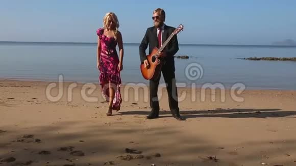 黎明时分穿着红色紧身衣的女孩在海滩上与吉他手拥抱视频的预览图