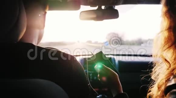 沿着高速公路朝太阳前进一对年轻夫妇正在夕阳的照耀下乘汽车旅行回去视频的预览图