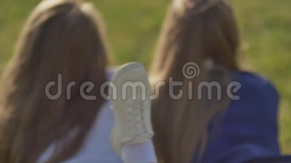 两个年轻快乐的女孩躺在绿草上视频的预览图