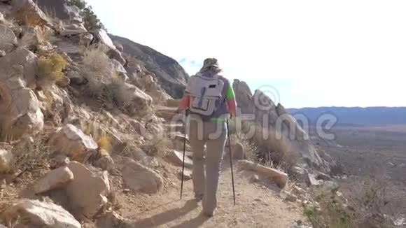 登山妇女沿着山径沿着悬崖借助旅行棒视频的预览图