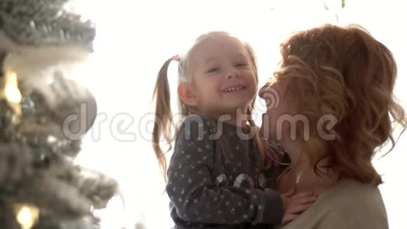 在装饰好的圣诞树上女人手牵着女儿的肖像那个金发女孩和视频的预览图
