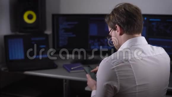 一位年轻的自由职业者身着白色衬衫手上拿着智能手表在家里的房间里使用电脑视频的预览图