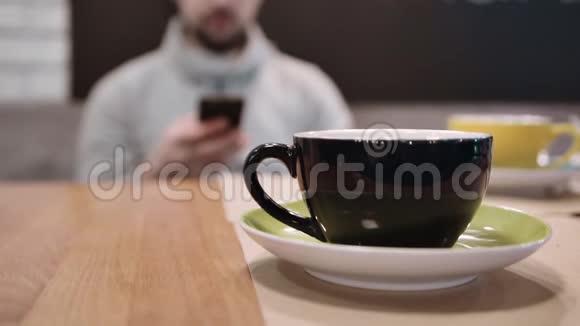 一个面目全非的人坐在餐厅里在一杯茶的离焦处接电话慢动作视频的预览图