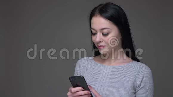 用灰色背景的手机拍摄白种人年轻漂亮女性的特写镜头视频的预览图