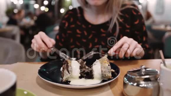 女孩在餐馆吃甜点用叉子和刀慢动作视频的预览图