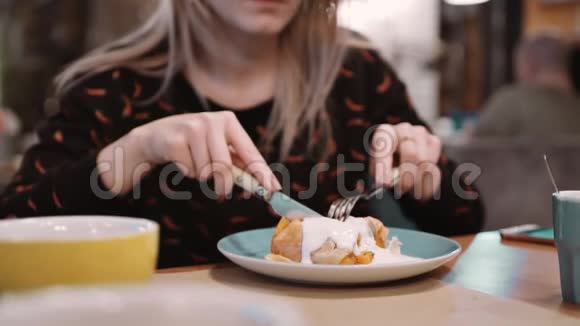 无法辨认的女孩在餐厅用叉子和刀子吃橙色甜点慢动作视频的预览图