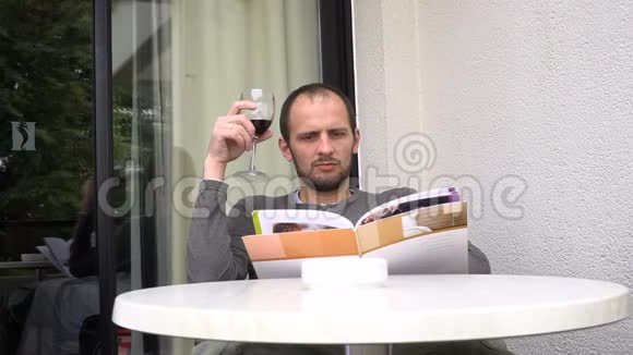 英俊的男人手里拿着杂志喝着一杯好酒视频的预览图