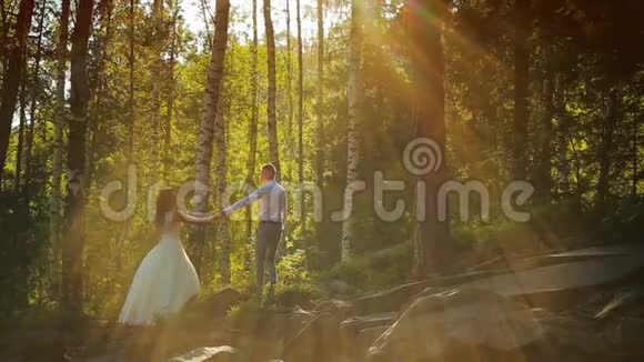 优雅幸福的新婚夫妇在日落时分在森林里接吻视频的预览图