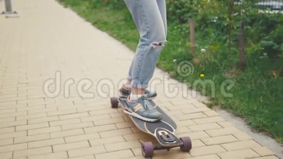 在街道上关闭女孩骑滑板长板慢动作视频的预览图