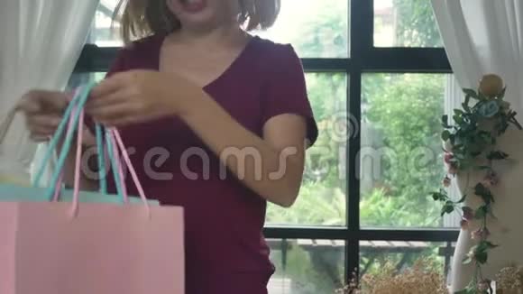 幸福的年轻亚洲女人带着购物袋在现代公寓检查购买视频的预览图