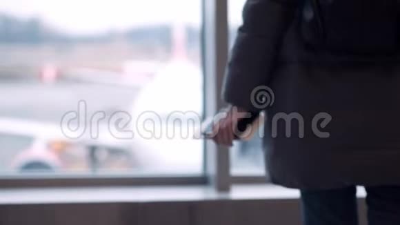 戴眼镜的年轻女孩或青少年戴着围巾看着机场的飞机拿着护照和机票视频的预览图
