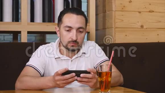 男人坐在咖啡馆里使用智能手机视频的预览图