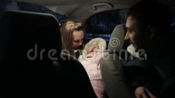 年轻夫妇带着新生婴儿坐在车里说话视频的预览图