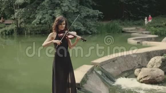 优雅的黑发小提琴家在户外的桥上演奏视频的预览图