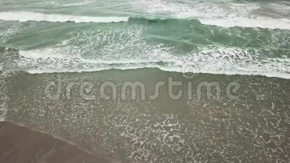 鸟瞰海洋蓝绿波浪在白沙滩上破碎美丽的海滩上的海浪鸟瞰无人机4k视频的预览图