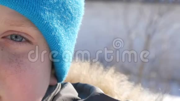 一个男孩戴着蓝帽子脸上长着蓝眼睛和雀斑看着镜头近距离观看视频的预览图