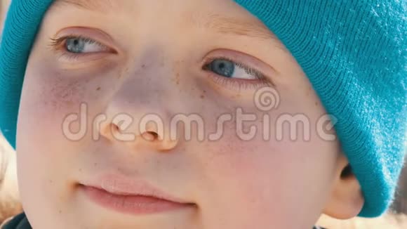 一个年轻的男孩他有着一双不寻常的蓝眼睛脸上有雀斑戴着一顶蓝色帽子看着一边视频的预览图