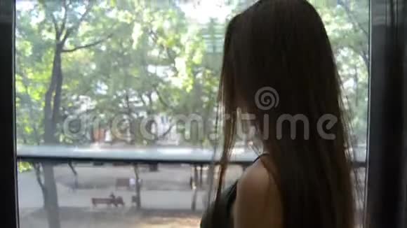 年轻迷人的黑发女郎爬在电梯里透明的墙壁视频的预览图
