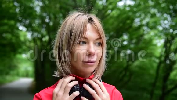 一个戴着耳机的金发美女在森林里户外慢跑的特写镜头视频的预览图