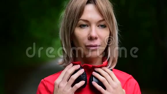 一个戴着耳机的金发美女在森林里户外慢跑的特写镜头视频的预览图