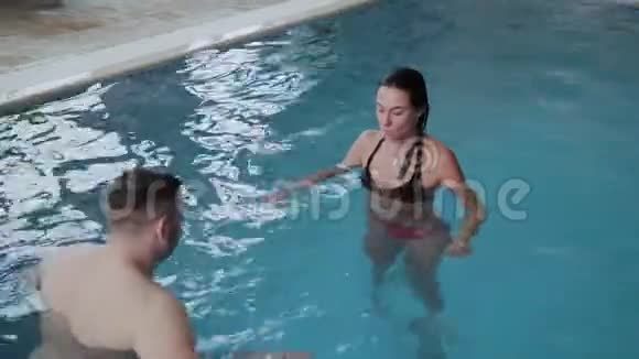 年轻的男人和女人在游泳池里开玩笑和微笑视频的预览图