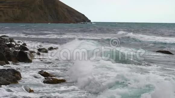 从撞击石岸的海浪中缓慢移动破碎的水滴Cerulean水丘向海岸倾斜视频的预览图