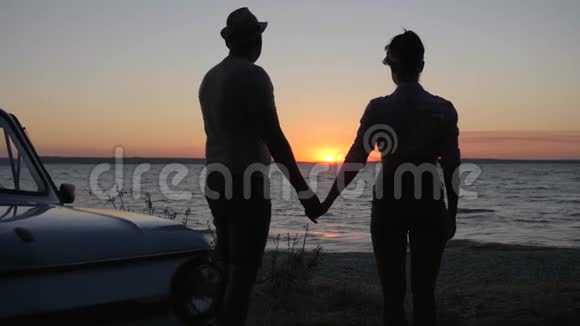双手相握的剪影黄昏时分的户外活动浪漫的海滨情人之旅视频的预览图