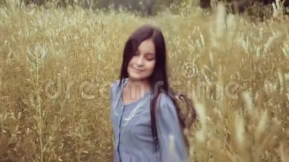 肖像一个美丽的小女孩走在高高的草地上幸福地微笑着视频的预览图