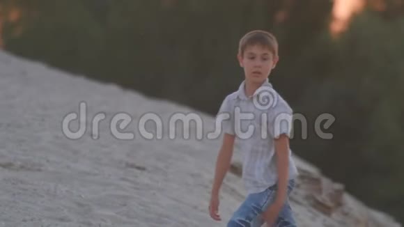 那个男孩在日落时沿着海滩散步孩子的积极休息视频的预览图