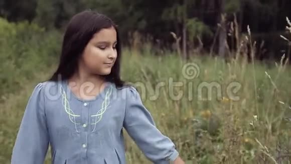 肖像一个美丽的小女孩正沿着森林里的小路走着甜甜地笑着视频的预览图