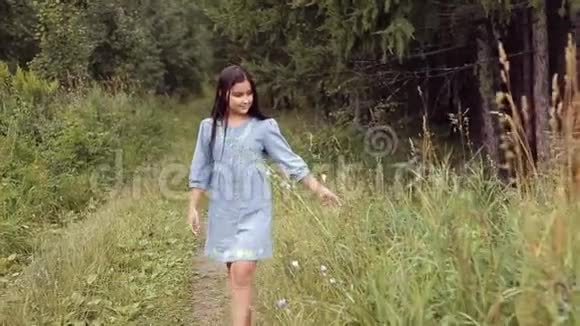 一个美丽的小女孩正沿着森林里的小路走着甜甜地笑着视频的预览图