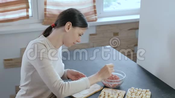 女人用肉馅包饺子看着镜头微笑视频的预览图