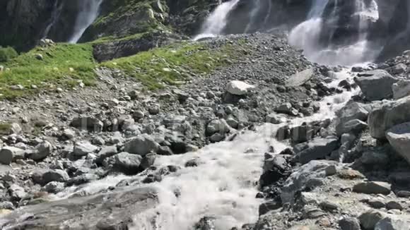 高山瀑布水流在阳光下落在岩石上在缓慢的运动中急速的水泼水视频的预览图