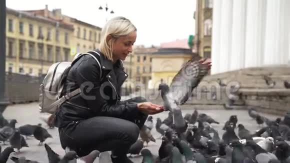 美丽的年轻女子在街上喂鸽子视频的预览图