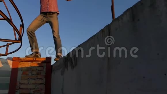 夏天日落时勇敢的人站在高高的水泥边上视频的预览图