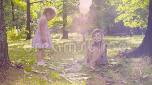 两个女孩在公园里树旁的草地上玩耍视频的预览图