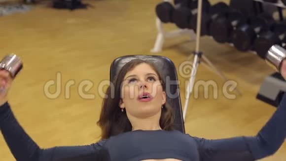 年轻的黑发在健身房锻炼手的重量视频的预览图