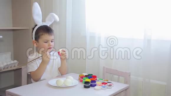 一个打扮成兔子的男孩在画一个复活节彩蛋视频的预览图