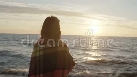 后景的黑发女子站在海边做梦年轻的女性享受海滩和日落视频的预览图