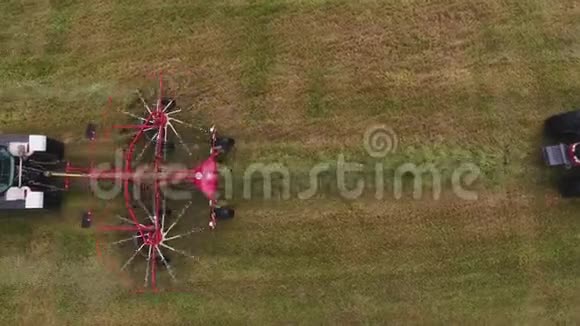 大灰拖拉机在田间用红色圆形耙子移动的俯视图视频的预览图