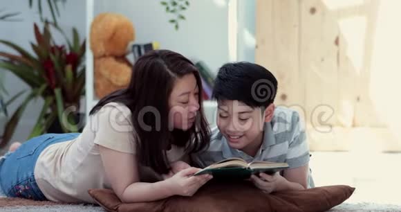 快乐的亚洲家庭母子在地板上休息一起读一本书视频的预览图