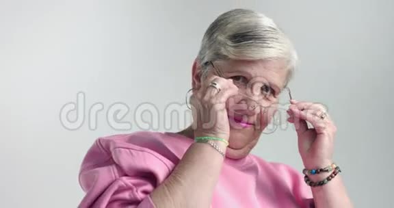 年长的女人戴上眼镜对着镜头观看视频的预览图