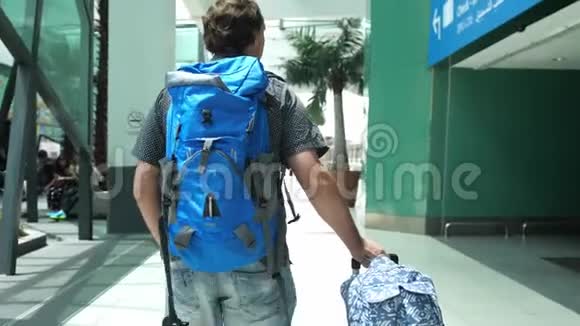 年轻男子背着背包在现代机场航站楼拉手提箱散步的帅哥视频的预览图