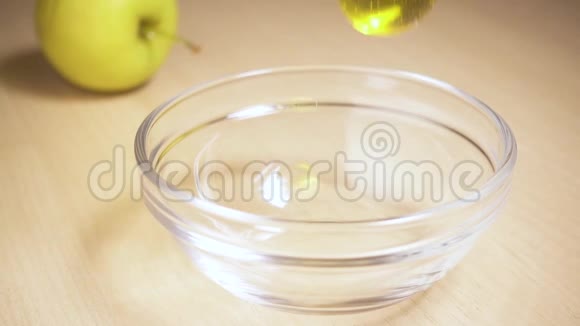 慢动作蜂蜜流入一个有苹果的桌子上的碗里视频的预览图