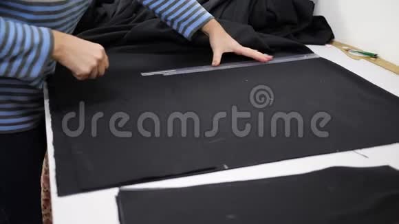工作中的裁缝用尺子测量车间桌子上的黑色组织视频的预览图