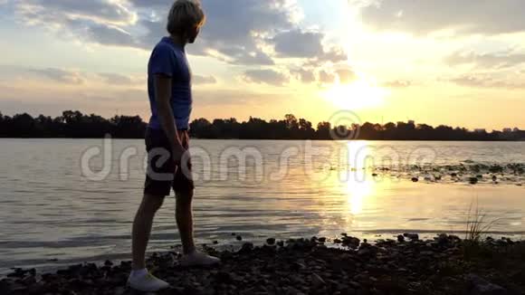 令人惊叹的日落和一个人在斯隆莫的河水中投掷扁平的石头视频的预览图