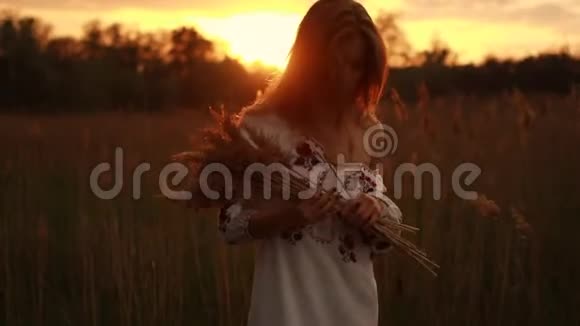 日落时分穿着乌克兰国家刺绣衬衫的年轻女子穿过草地视频的预览图