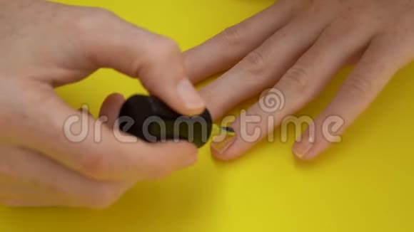一个女孩在黄色背景下把指甲涂成黄色的特写镜头黄色概念视频的预览图