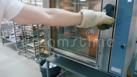 专业面包师在商业厨房从烤箱中取出甜面包店视频的预览图