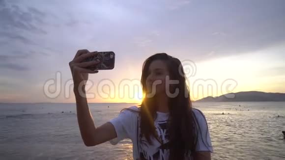 女人在海洋日出前的智能手机上自拍视频的预览图